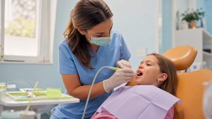 Dental hygienist scaling child's teeth